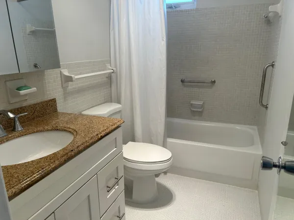 a bathroom with a granite countertop sink toilet and shower