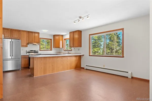 a kitchen with stainless steel appliances granite countertop a sink a stove a refrigerator a center island and a cabinets