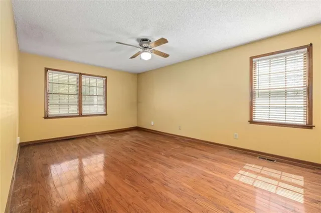 a view of an empty room with a window and wooden floor