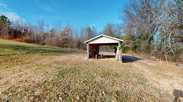 a view of a wooden house with a yard and large tree