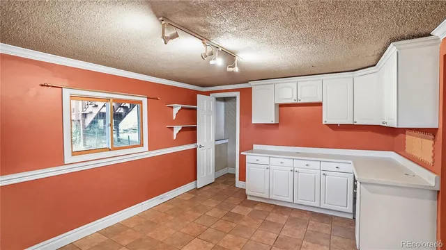 a view of a refrigerator in kitchen and an empty room with wooden floor