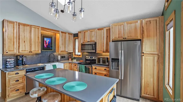 a kitchen with stainless steel appliances granite countertop a refrigerator a stove top oven a sink dishwasher and wooden cabinets with wooden floor