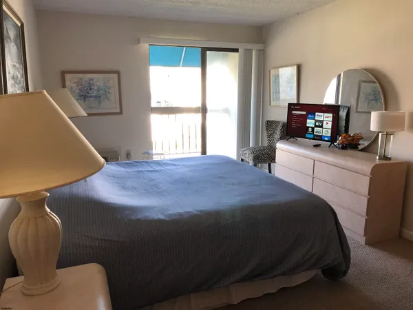 a bedroom with a bed next to a window with a chair