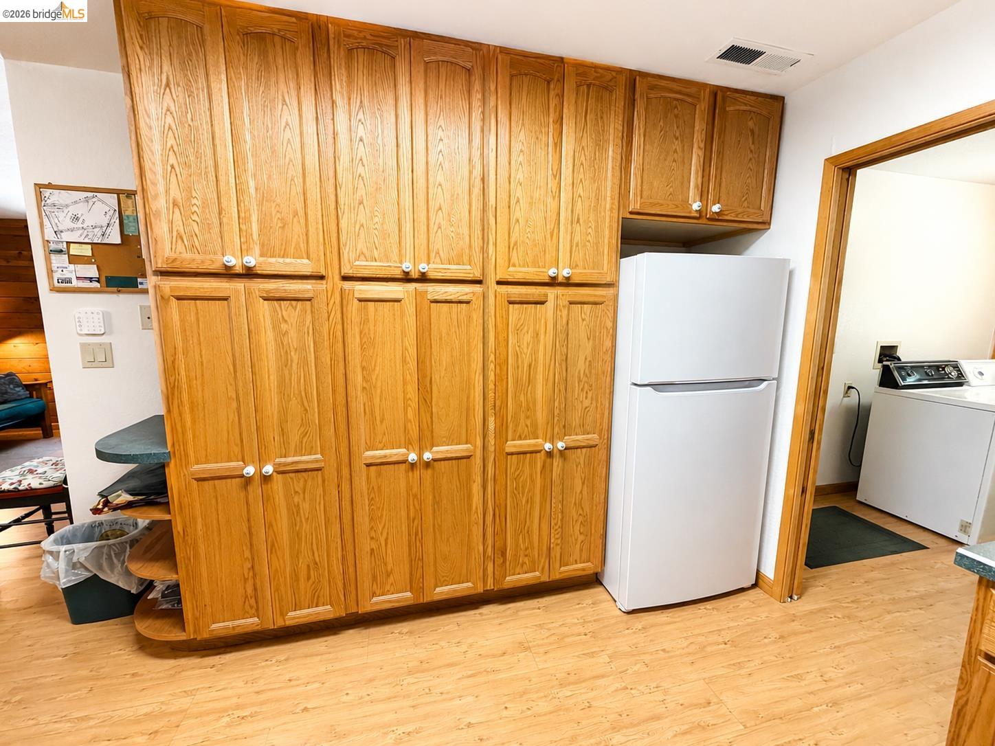 21181 Phoenix Lake Road Sonora, CA 95370 - Photo 20 of 34 Extensive wood cabinetry with white knob hardware, light wood-finish flooring, and a built-in shelving unit