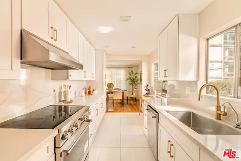 a large kitchen with stainless steel appliances a sink a stove and cabinets
