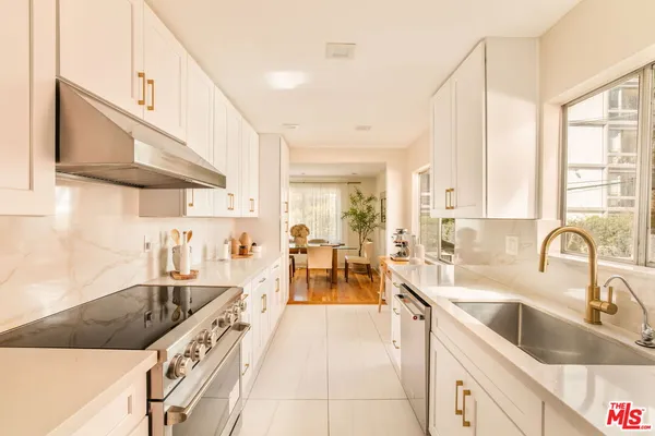 a large kitchen with stainless steel appliances a sink a stove and cabinets