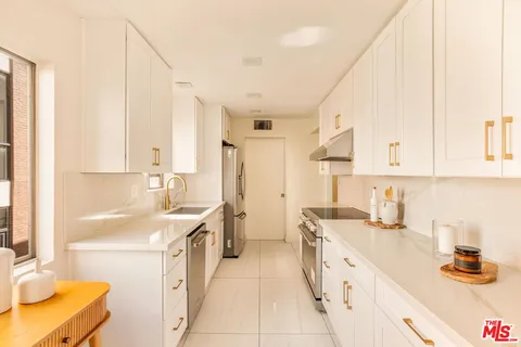 a large white kitchen with a sink a stove a bathtub and a window