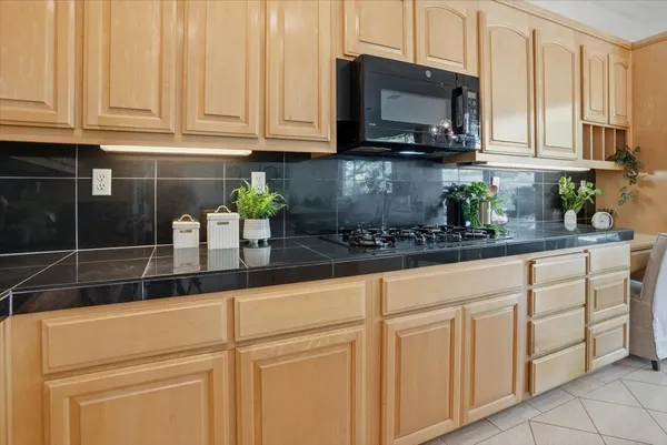 a kitchen with stainless steel appliances granite countertop a refrigerator a stove a sink a dining table and chairs with wooden floor