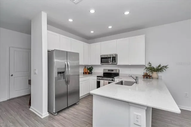 a kitchen with stainless steel appliances a sink a refrigerator and a counter top space
