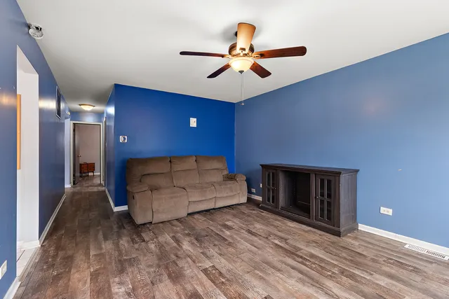 a living room with a bed furniture and a ceiling fan