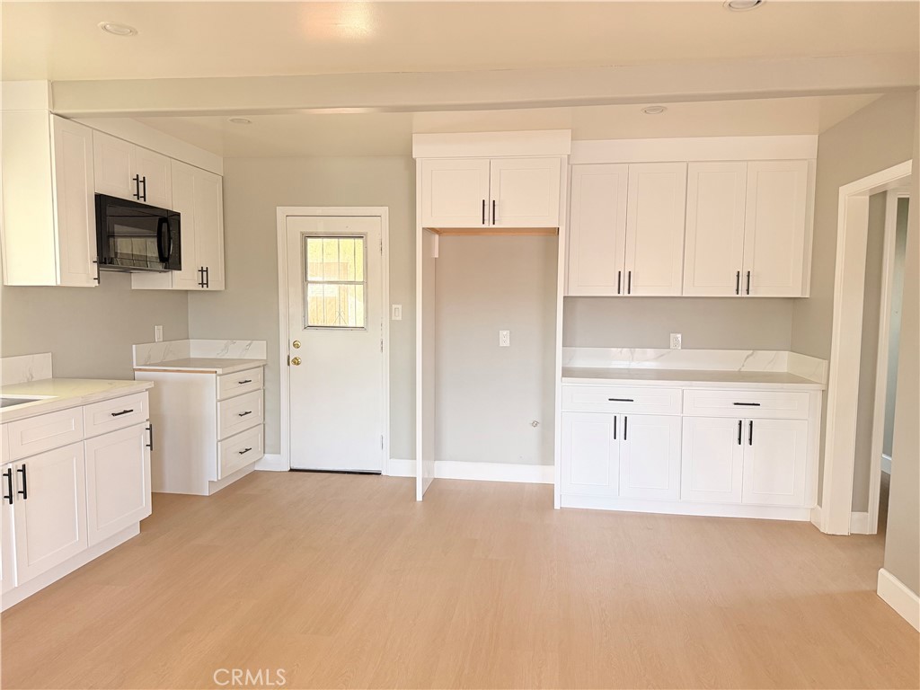 8803 Laurel Street Bellflower, CA 90706 - Photo 6 of 18 a view of a kitchen with white cabinets and stainless steel appliances