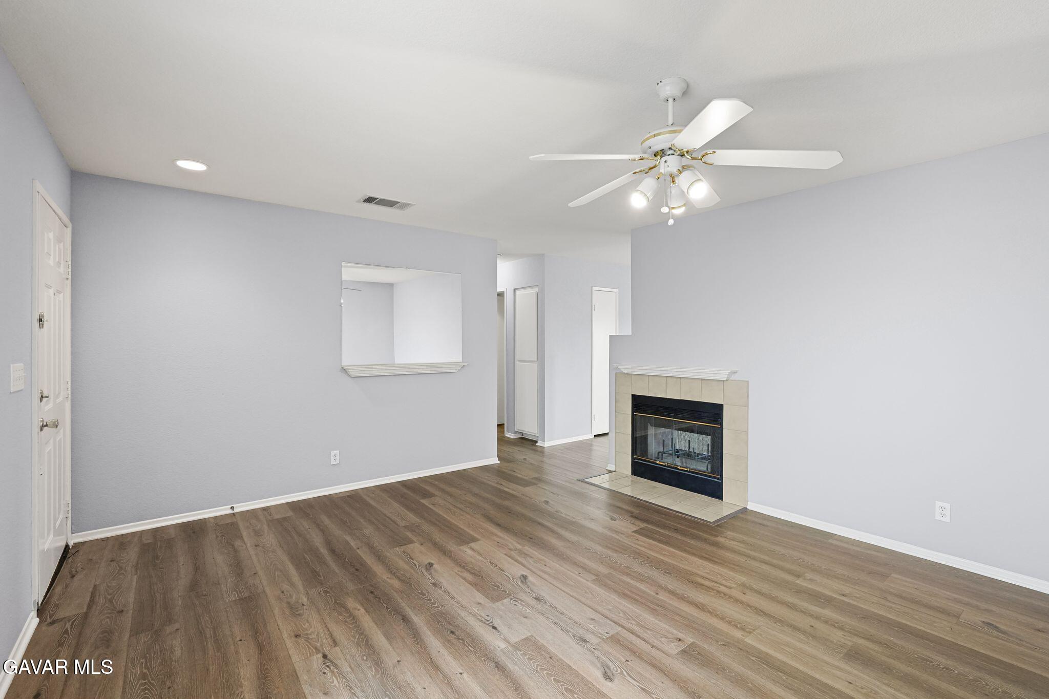 2108 Manchester Street Rosamond, CA 93560 - Photo 14 of 41 an empty room with wooden floor a ceiling fan and fireplace