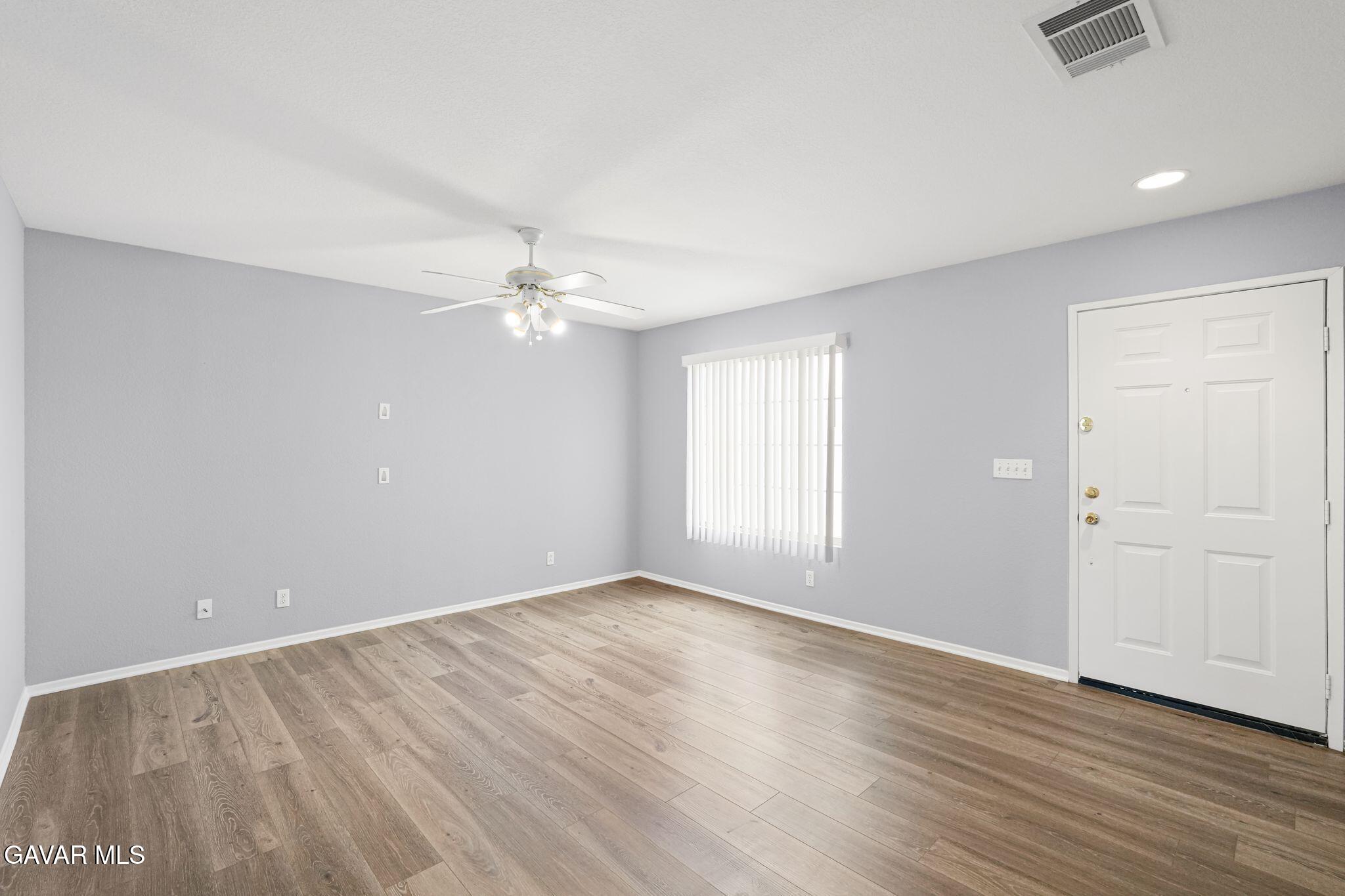 2108 Manchester Street Rosamond, CA 93560 - Photo 15 of 41 an empty room with wooden floor chandelier fan and windows