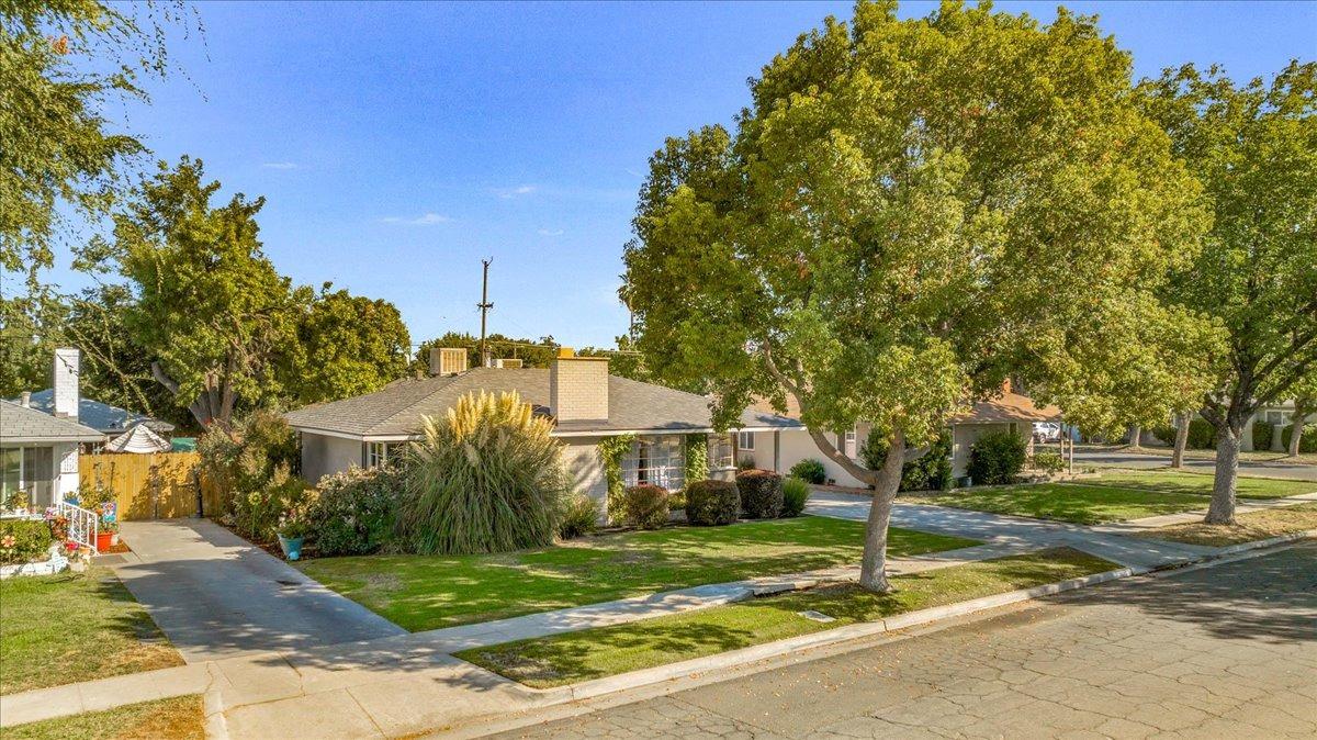 a view of a white house next to a yard with big trees