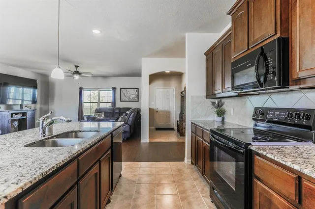a kitchen with granite countertop a sink a stove and cabinets