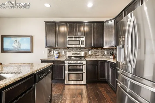 a kitchen with stainless steel appliances granite countertop a stove and a refrigerator