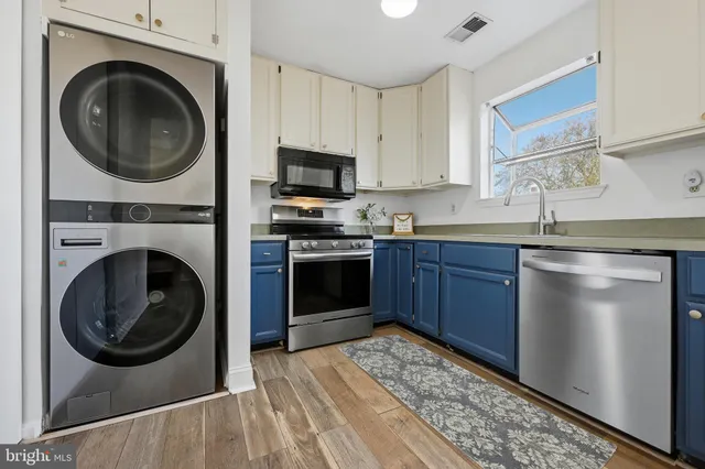 a kitchen with stainless steel appliances granite countertop a sink a stove a washer and dryer