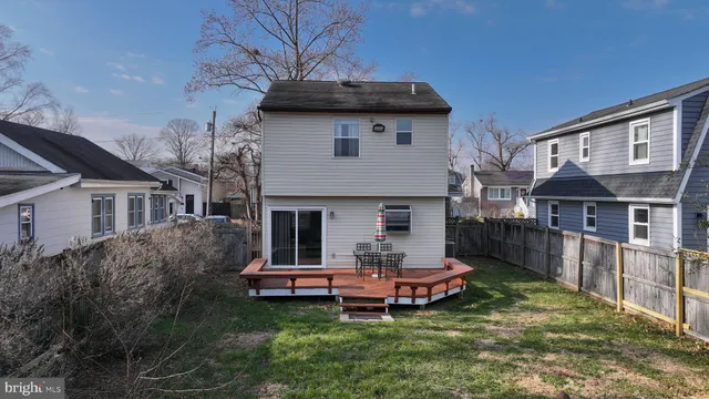 a white house that has a small yard and large trees
