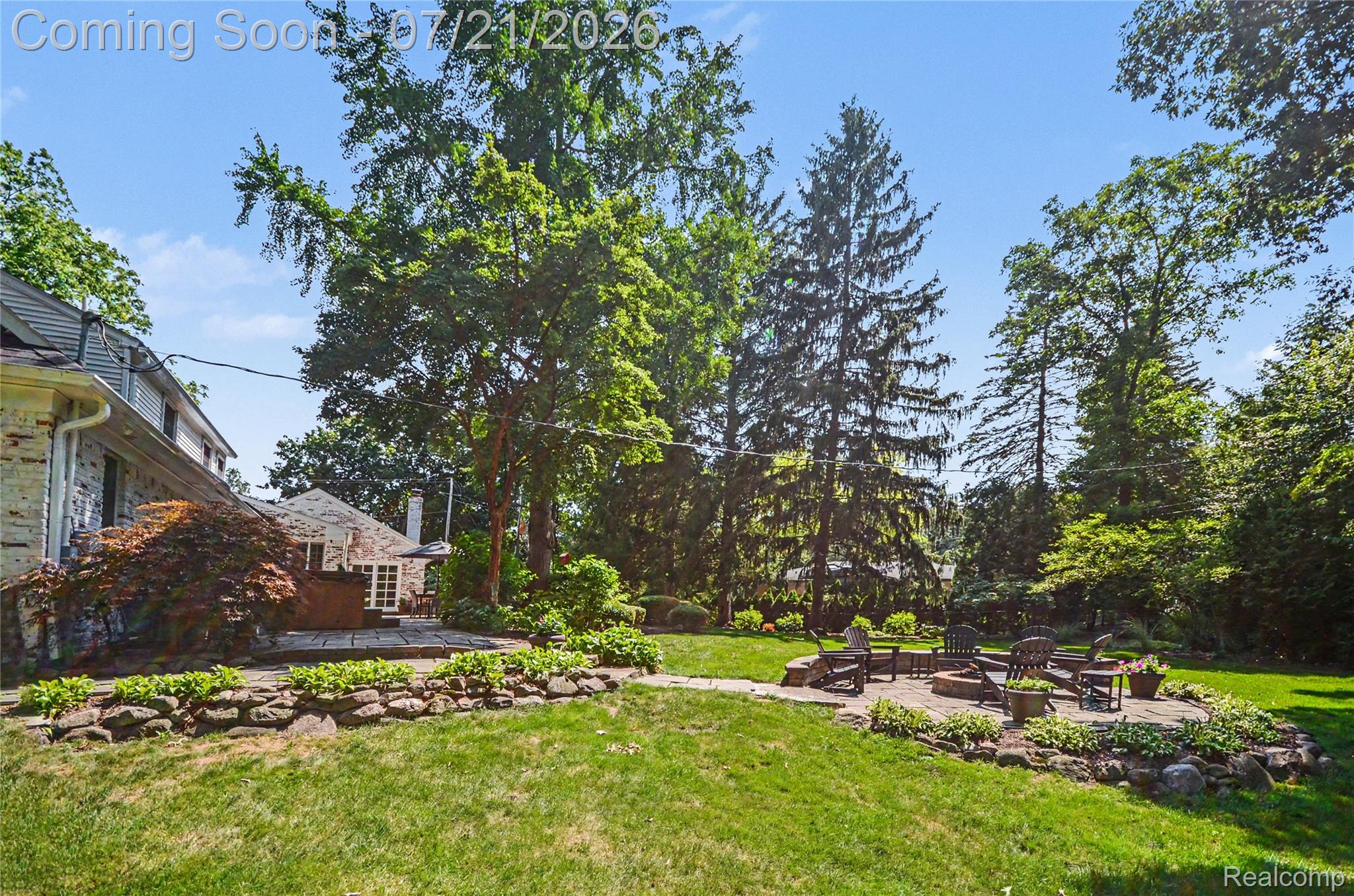 3780 Squirrel Road Bloomfield Hills, MI 48304 - Photo 44 of 59 Expansive backyard featuring a stone patio with a built-in fire pit, surrounded by mature trees