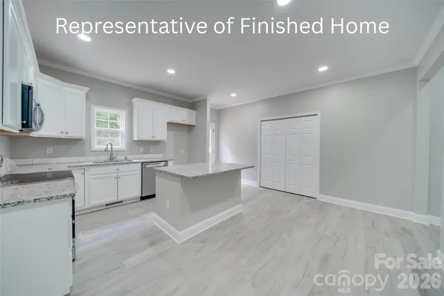 a large kitchen with stainless steel appliances granite countertop a stove a sink and white cabinets