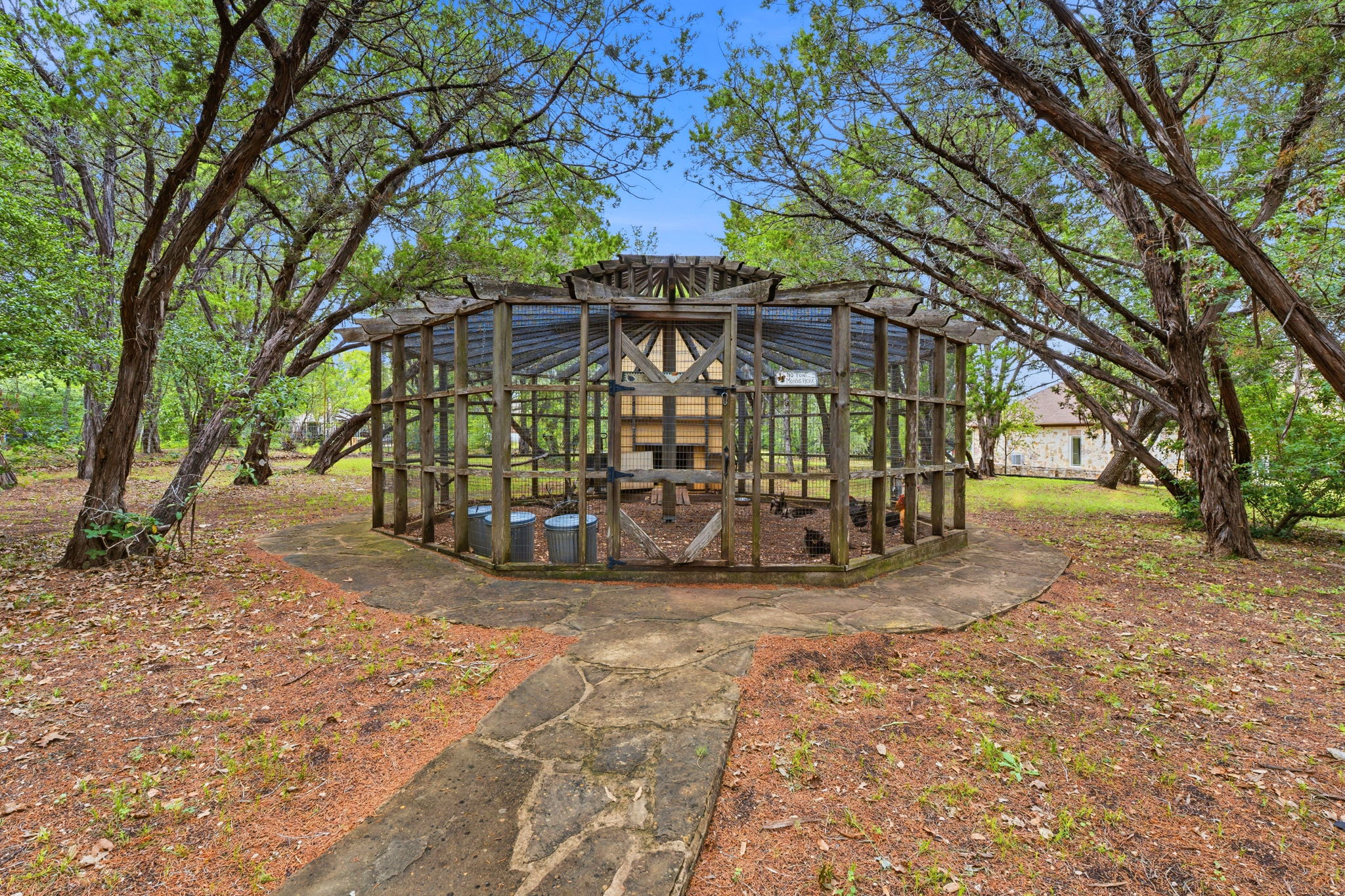 8121 Bluff Trail Austin, TX 78737 - Photo 36 of 40 A rustic aviary, nestled among mature trees, provides a charming outdoor amenity.