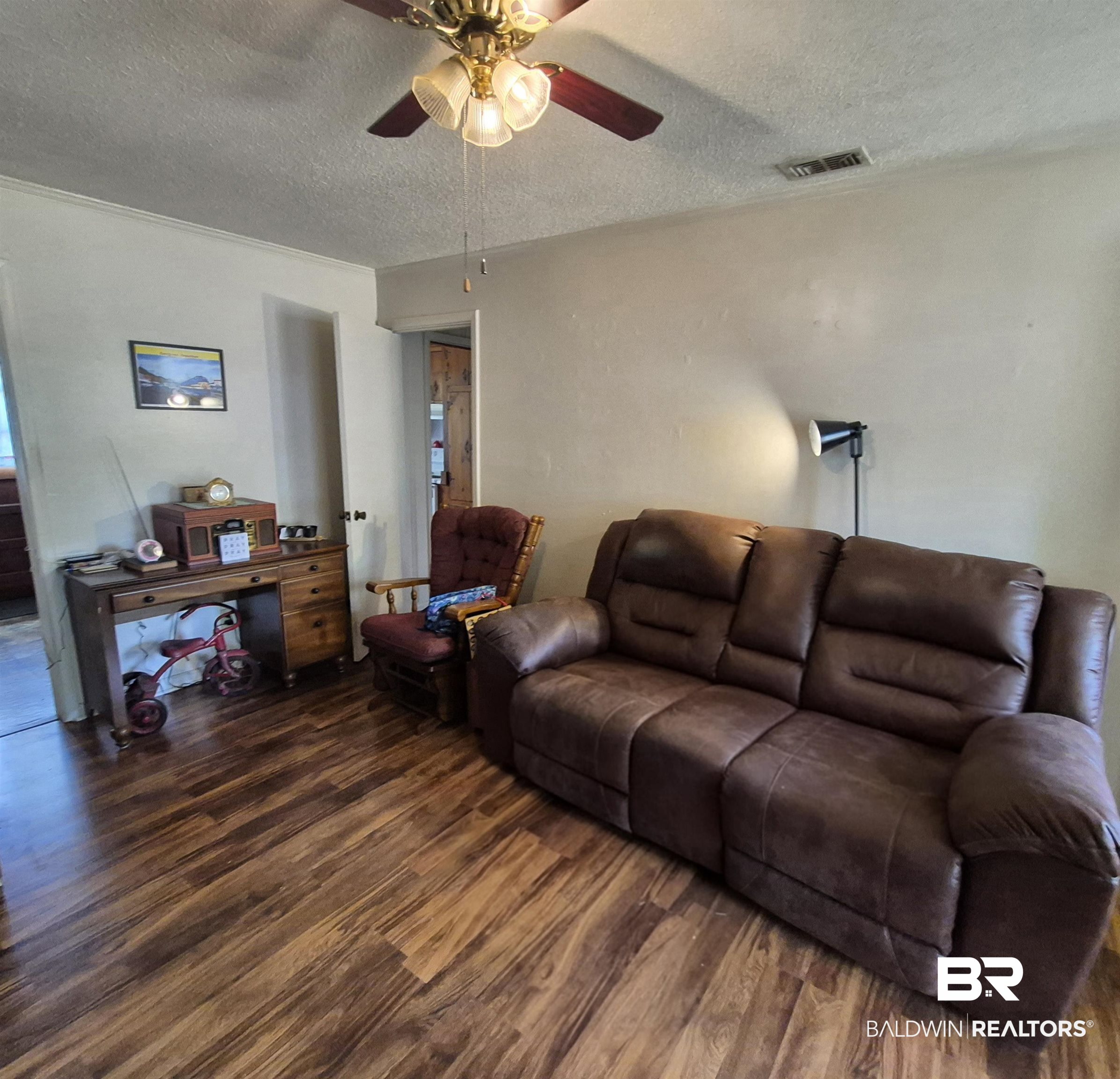 108 Azalea Street Evergreen, AL 36401 - Photo 5 of 19 Wood-finish flooring throughout, complemented by a ceiling fan with integrated lighting