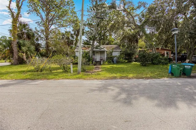 a view of a house with a yard and large trees
