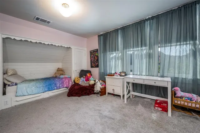 a bedroom with a bed a study table and large window