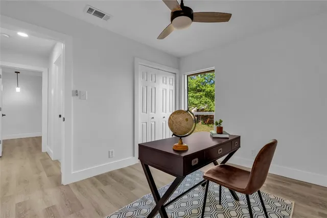 a view of empty room with wooden floor and fan