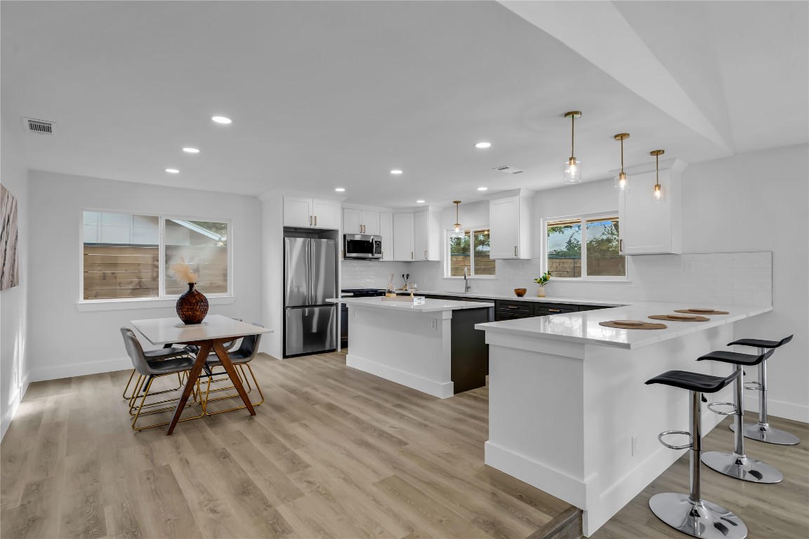 11602 Big Trail Austin, TX 78759 - Photo 5 of 27 a kitchen with stainless steel appliances kitchen island hardwood floor sink stove dining table and chairs