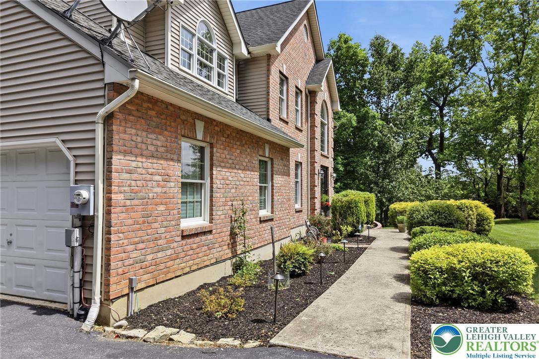 115 West Butternut Road Hellertown, PA 18055 - Photo 92 of 97 Timeless brick and siding exterior blends with verdant landscaping and mature trees, creating inviting curb appeal.