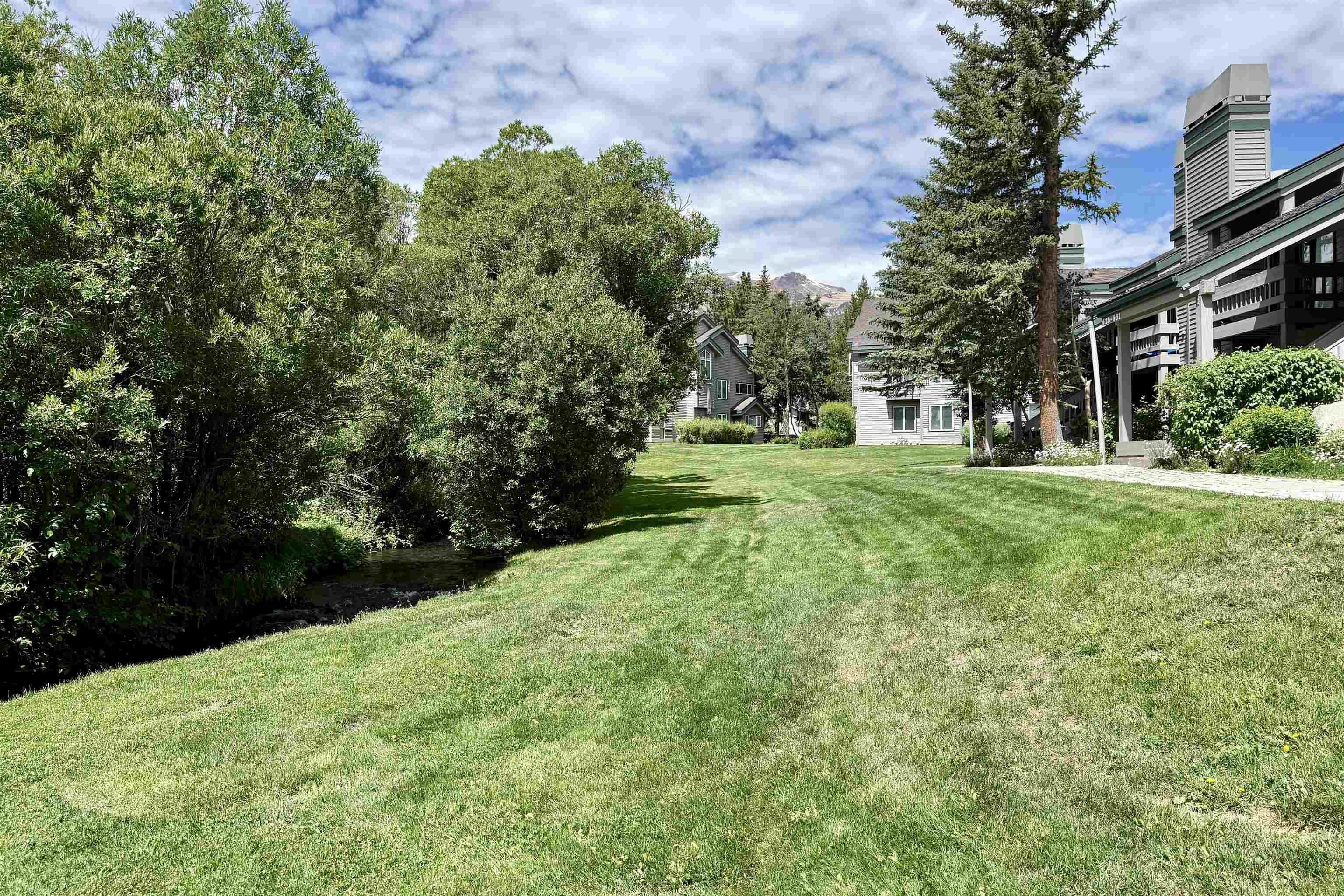 625 Golden Creek Road, Unit 625 Mammoth Lakes, CA 93546 - Photo 34 of 37 Expansive green lawn bordering a natural water feature with mature foliage