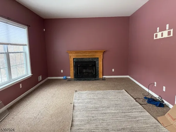 a view of an empty room with a fireplace and a window