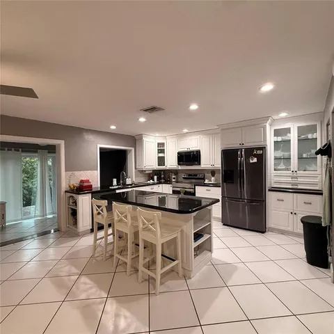a kitchen with stainless steel appliances kitchen island granite countertop a refrigerator and a stove top oven