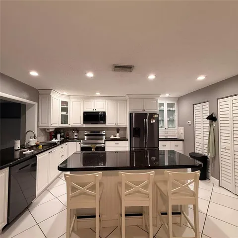 a kitchen with stainless steel appliances kitchen island granite countertop a refrigerator and a stove top oven with wooden floor