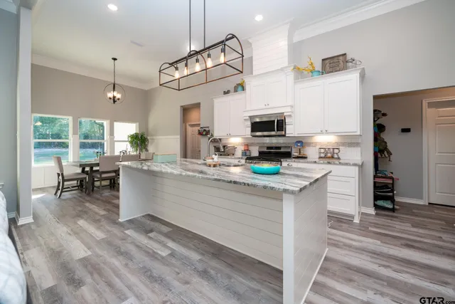 a kitchen with kitchen island granite countertop a sink cabinets and stainless steel appliances