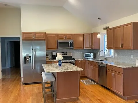 a kitchen with stainless steel appliances granite countertop a stove a sink dishwasher a refrigerator and a microwave oven with wooden floor