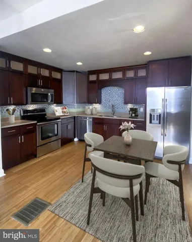 a kitchen with stainless steel appliances granite countertop a table chairs sink refrigerator and microwave