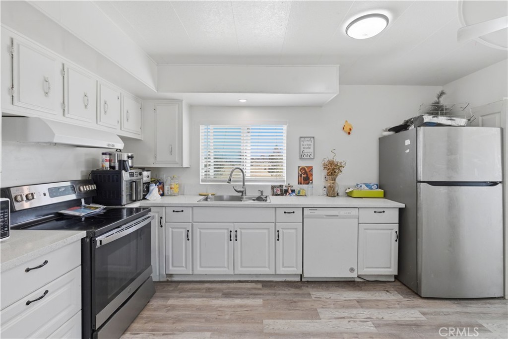 5885 Dos Palmas Road Phelan, CA 92371 - Photo 10 of 40 a kitchen with a sink white cabinets and stainless steel appliances