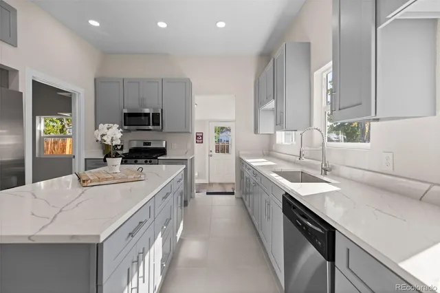 a large kitchen with kitchen island granite countertop a sink a stove counter space and cabinets