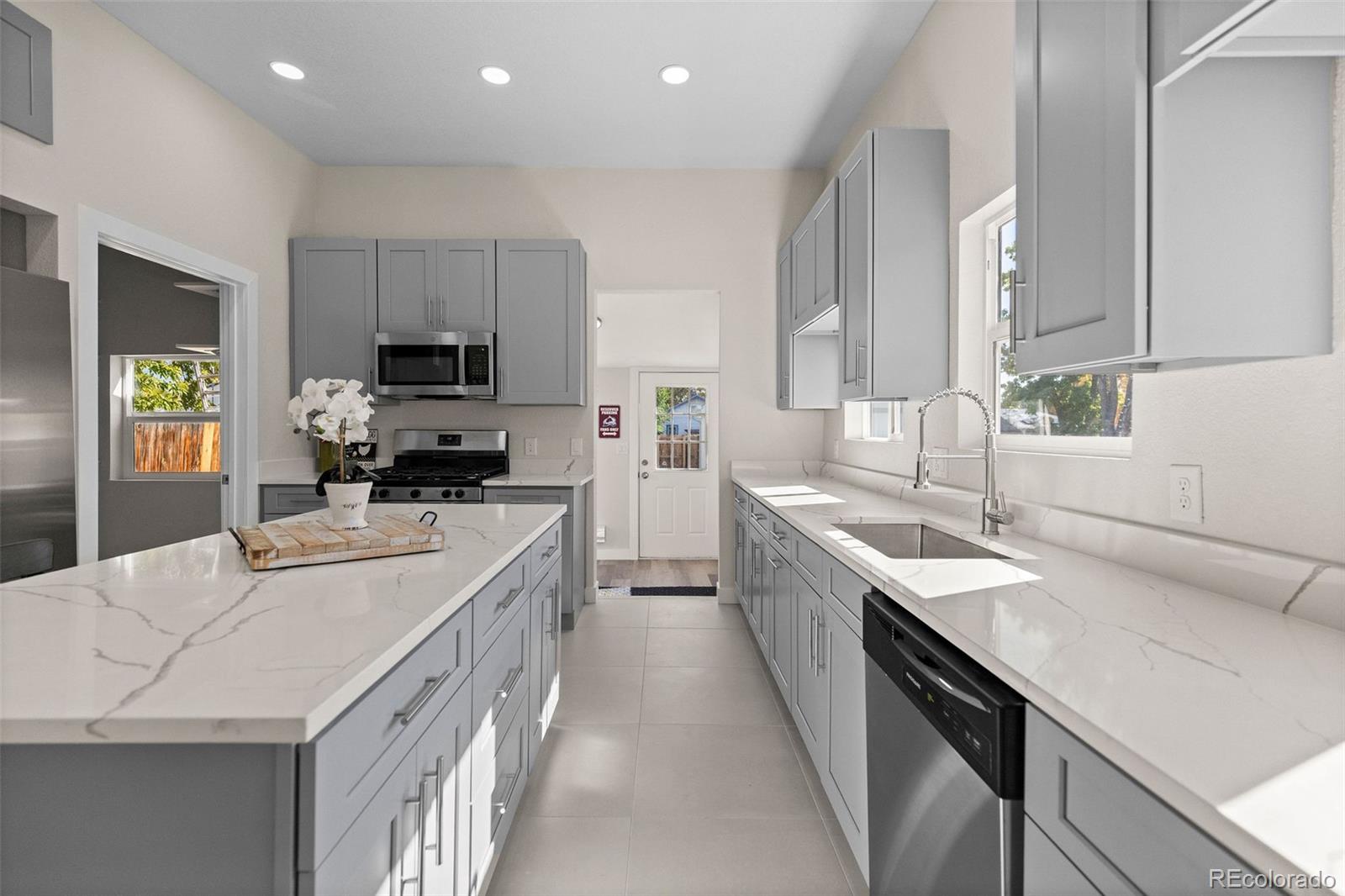 146 Stuart Street Denver, CO 80219 - Photo 9 of 31 a large kitchen with kitchen island granite countertop a sink a stove counter space and cabinets