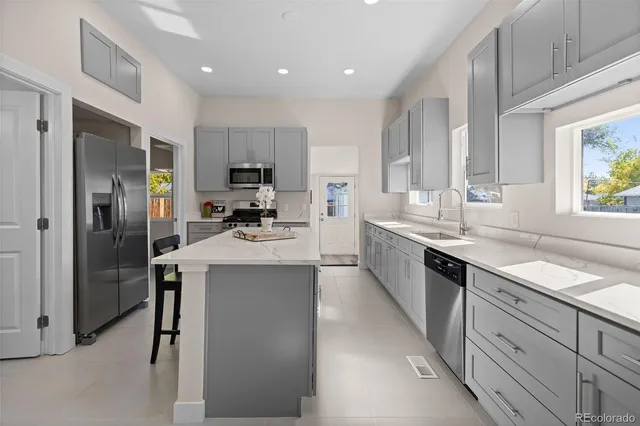 a large kitchen with stainless steel appliances kitchen island granite countertop a sink refrigerator and cabinets