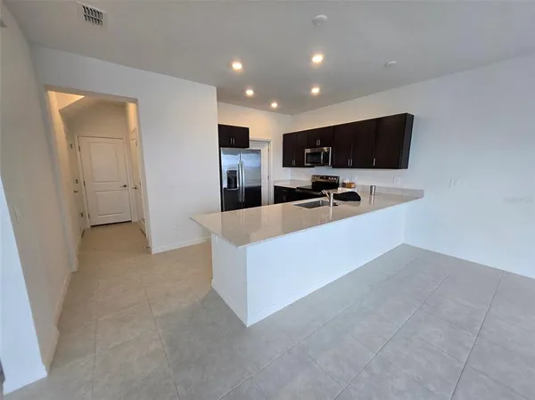 a living room with stainless steel appliances kitchen island furniture a flat screen tv and a sink