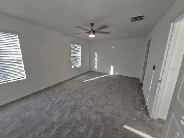 en empty room with windows and ceiling fan