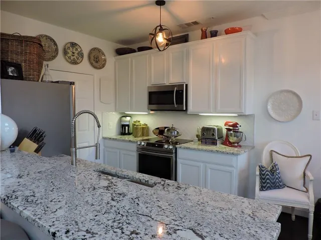 a kitchen with granite countertop a stove a sink and a microwave