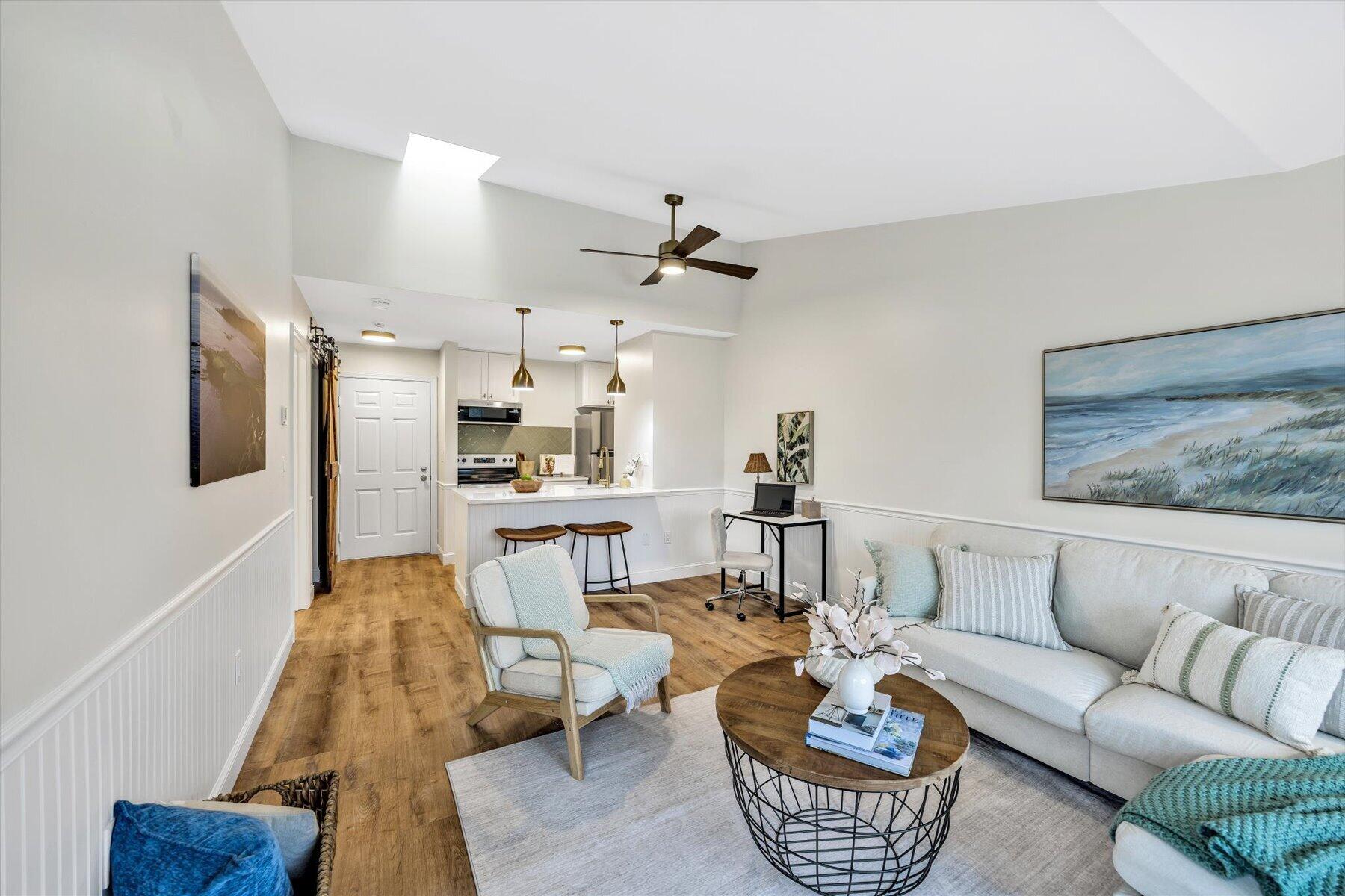 a living room with furniture a rug and kitchen view