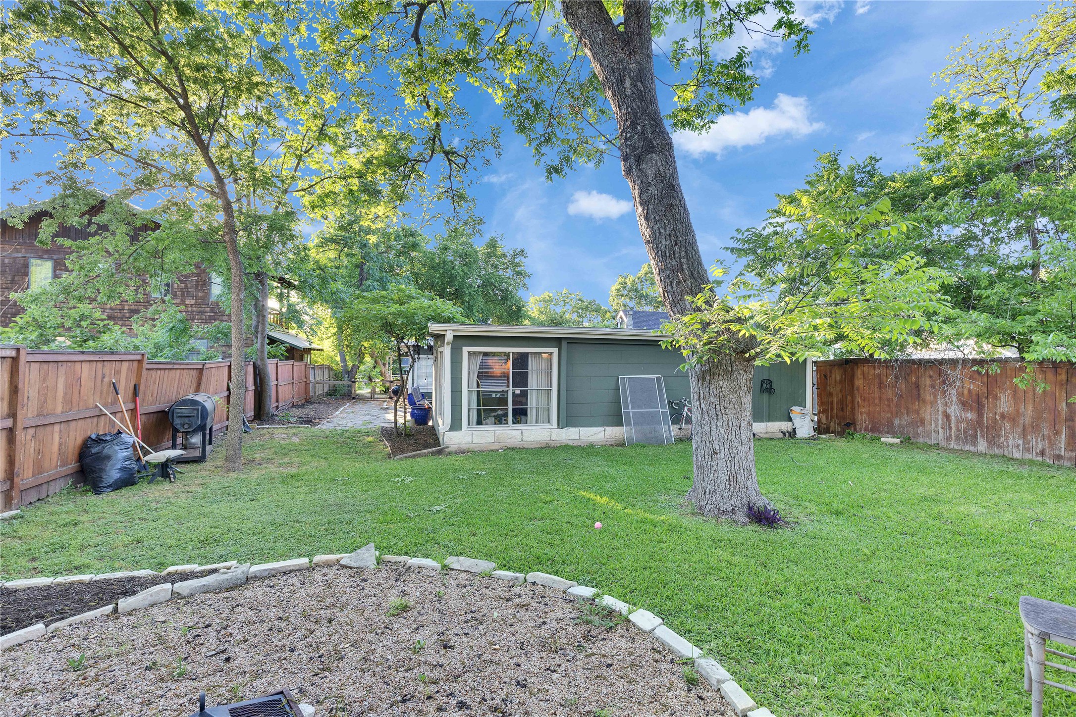 4607 Evans Avenue, Unit B Austin, TX 78751 - Photo 30 of 34 Expansive backyard featuring a large tree, manicured lawn, and a defined garden bed with stone edging