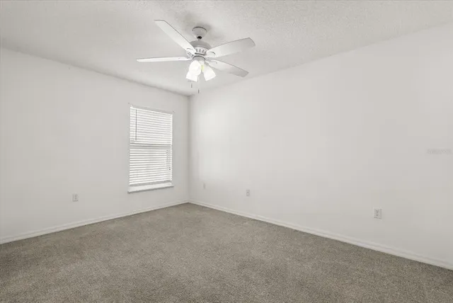 an empty room with a window and a fan