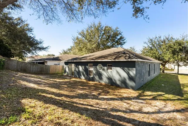 a view of a wooden house with a big yard and large trees