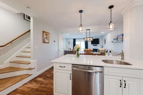 a kitchen with stainless steel appliances kitchen island granite countertop a sink a refrigerator and a view of living room
